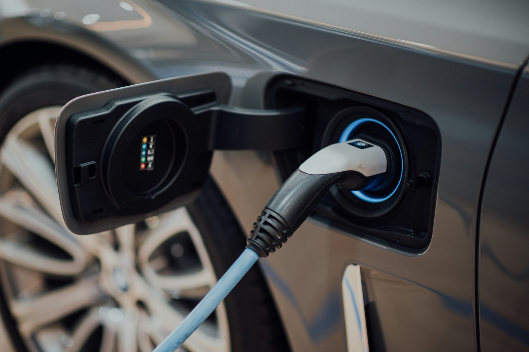 prise de recharge branchée sur une voiture électrique grise, connecteur et câble visibles en gros plan