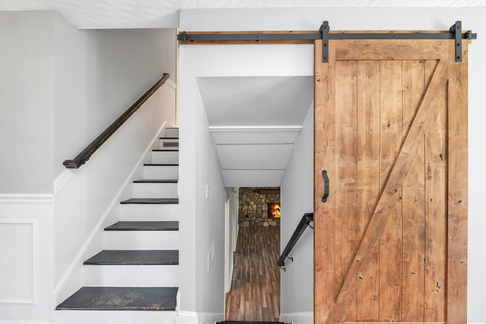 Porte coulissante en bois montée sur rail en applique, au pied d'un escalier