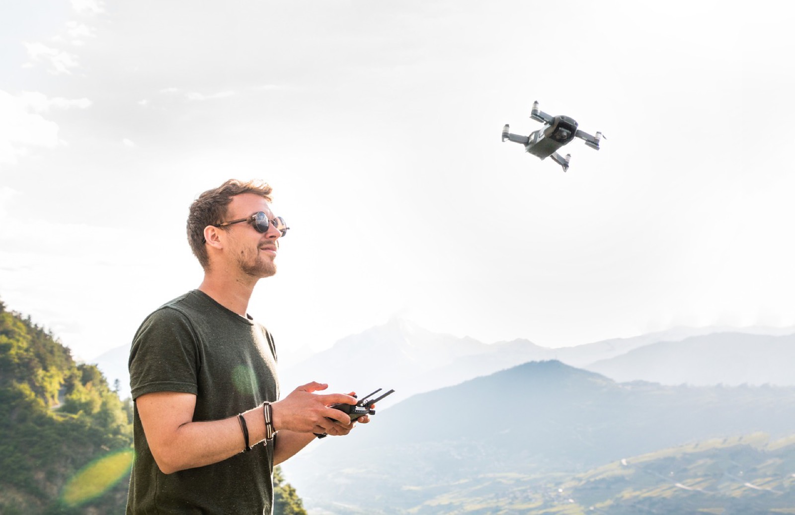 Télépilote tenant sa radiocommande dans un champ avant un vol de drone